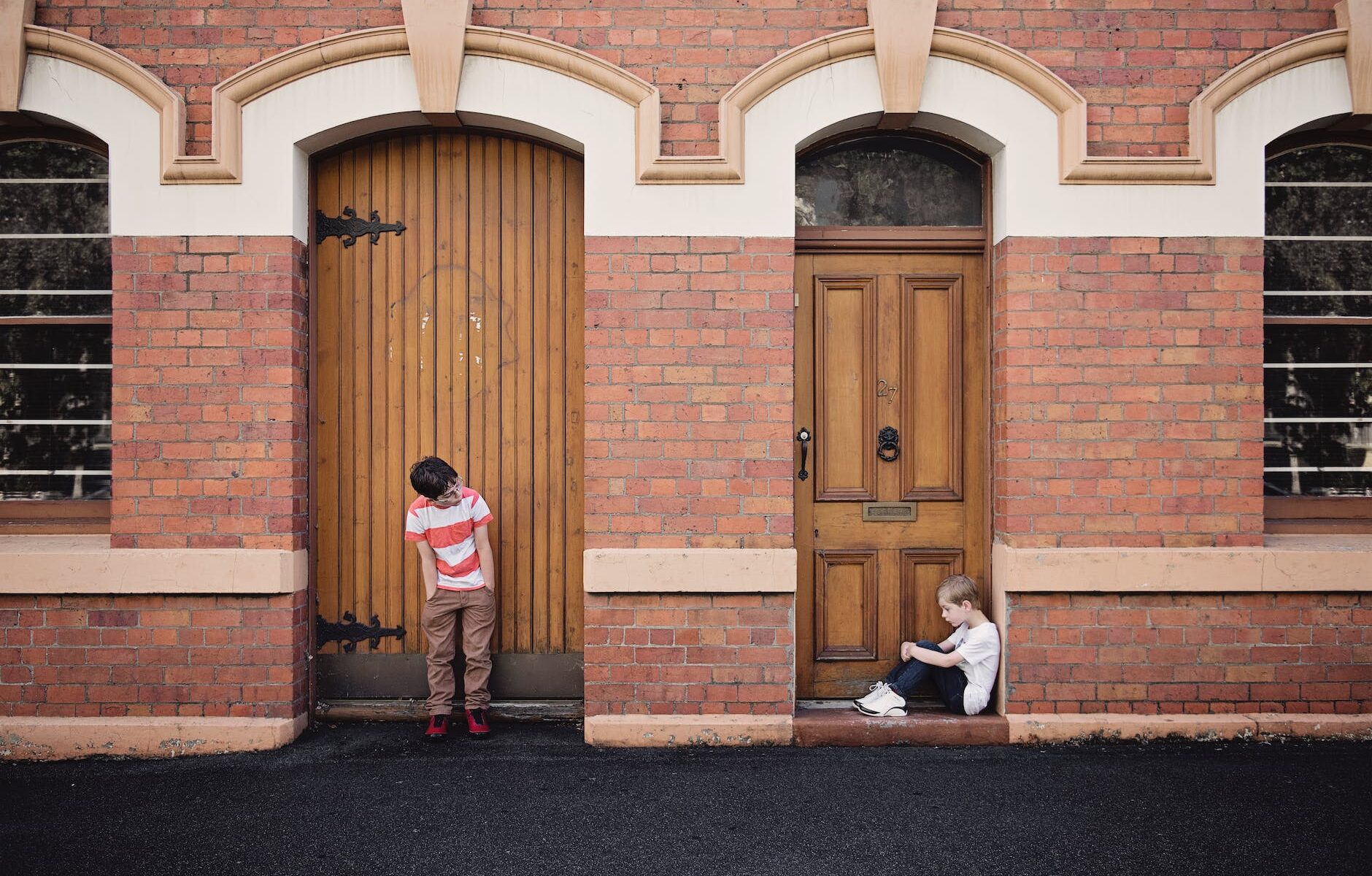 two children standing and sitting beside doors