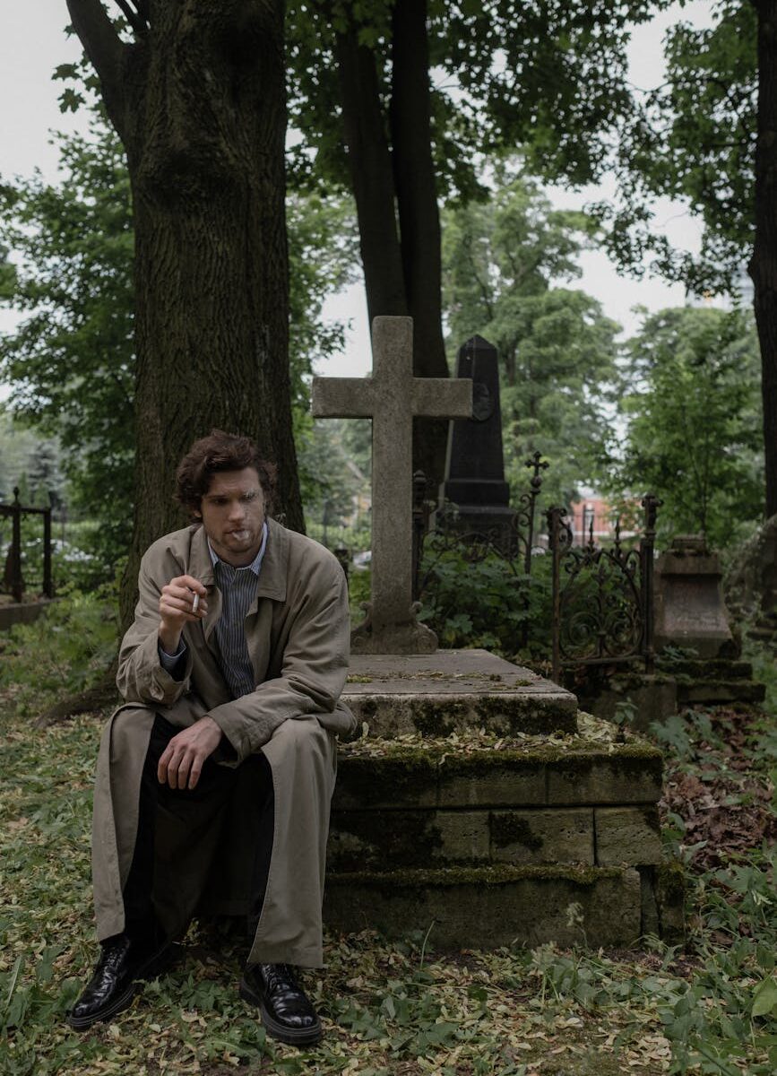 a man smoking a cigarette while sitting on a grave