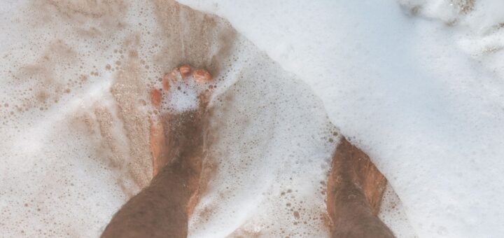 ocean water washing over man s feet