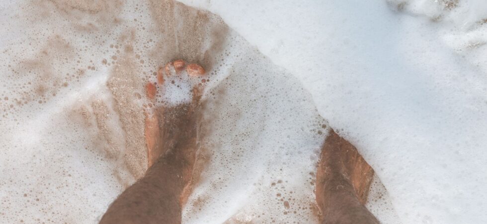 ocean water washing over man s feet