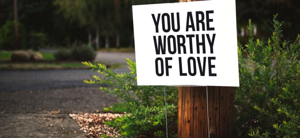 you are worthy of love signage on brown wooden post taken